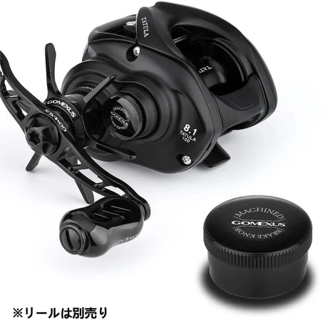Eine schwarze Daiwa Tatula-Rolle mit COMEXUS-Logo und einer Übersetzung von 8,1 ist neben einer schwarzen, runden Gomexus-Aluminium-Spulenspannknopfkappe mit der Aufschrift MACHINED COMEXUS abgebildet. In der unteren linken Ecke befindet sich japanischer Text.