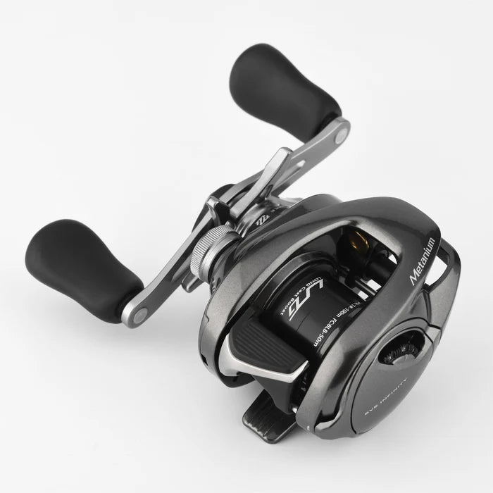 Die Gomexus Flat Spool BFS Spule Aluminium für Shimano 20 & 22 Metanium ist eine schwarz-silberne Baitcasting-Rolle mit zwei ergonomischen Griffen, einem seitlichen Einstellknopf und sichtbaren BFS-Tuning-Komponenten, dargestellt auf einem schlichten weißen Hintergrund.