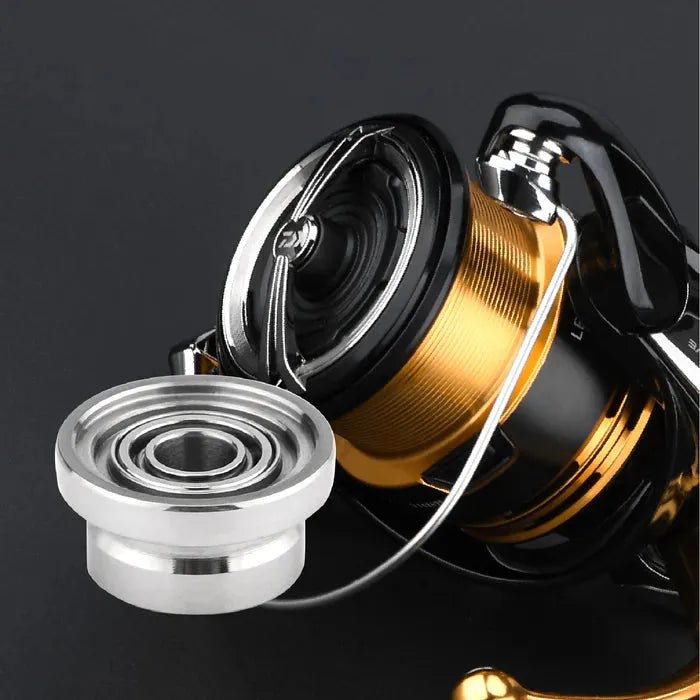 Eine Nahaufnahme eines Gomexus Schnurlaufröllchens für Daiwa 23 Regalis, die die Metallspule und ein separates silbernes Bauteil im Vordergrund zeigt, vor einem schwarzen Hintergrund. Marke: Gomexus.