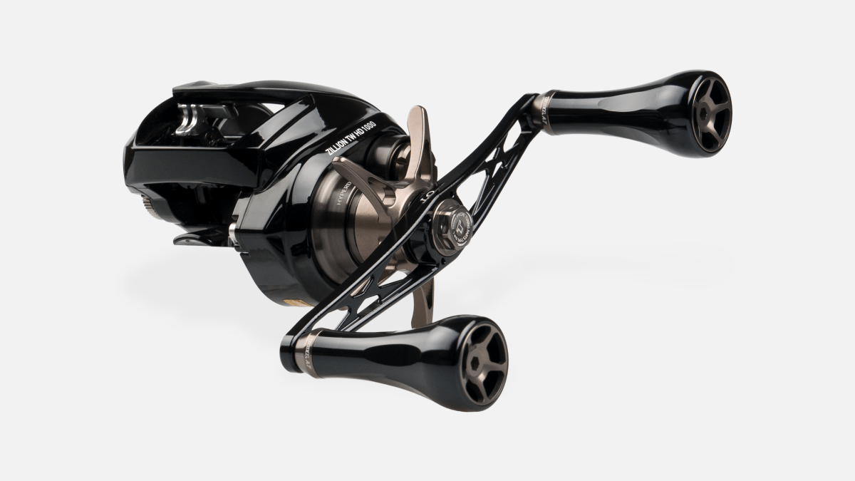 Der Taken GT106 Handle von Taken ist ein schwarzer Power Handle aus Duraluminium mit zwei großen A7 Aluminiumknöpfen für Shimano & Daiwa, abgebildet auf einer schlanken kompakten Rolle vor einem schlichten weißen Hintergrund.