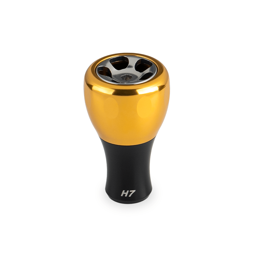 Der Taken H7 Knob 40mm von Taken ist ein goldener Aluminium-Stimmknopf für Baitcaster und Spinnrollen (Shimano und Daiwa). Er hat eine metallische Oberfläche mit vier kreisförmigen Aussparungen und einer "H7"-Markierung auf weißem Hintergrund.