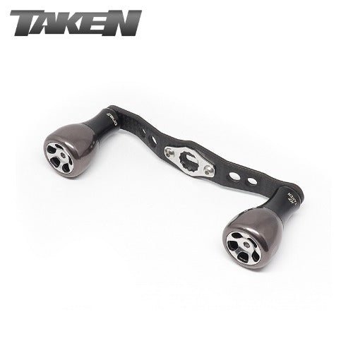 Der Taken H7 SS Crossover Carbon Handle 100 mm verfügt über gunmetalfarbene H7 Aluminiumknöpfe und einen Carbon Power Handle, der für Shimano & Daiwa entwickelt wurde. Auf weißem Grund mit dem Taken-Logo in der oberen linken Ecke.