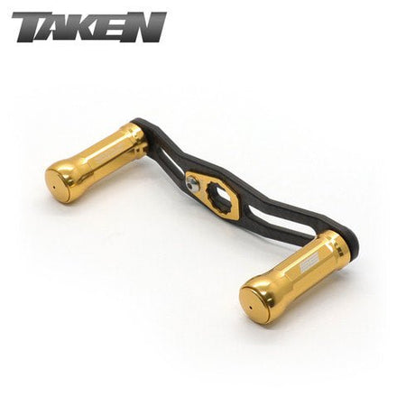 Ein goldener Taken SS Carbon Griff 85 mm mit zwei SS Aluminium Knöpfen für Shimano & Daiwa. Oben links ist "TAKEN" abgebildet und zeigt dieses fein abgestimmte Baitcaster-Zubehör.