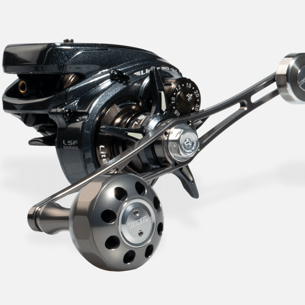 Eine Nahaufnahme des Taken X3 Knob 50mm von Taken, ein Power Tuning Griffknopf für Shimano & Daiwa Angelrollen (Hecht & Bigbait), zeigt metallische Ziffernblätter und komplizierte Teile vor einem schlichten hellen Hintergrund.