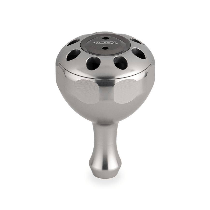 Der Taken X3 Knob 50mm von Taken ist ein kuppelförmiger Power Tuning Griff aus Titan für Shimano & Daiwa Rollen. Er hat eine glatte Oberfläche, runde Aussparungen an der Oberseite, "TITAN" auf einer schwarzen Mittelkappe und verjüngt sich zu einem schmalen Griff.
