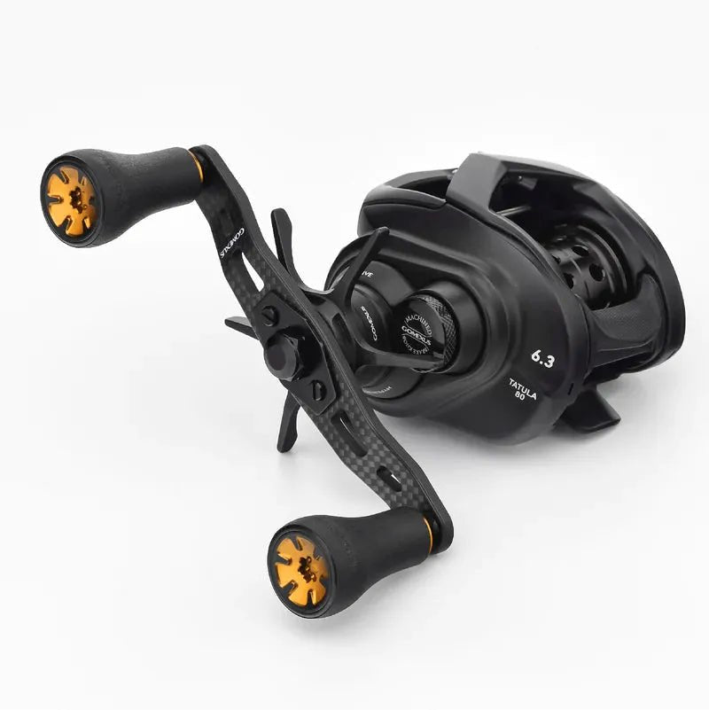 Eine schwarze Baitcasting-Rolle mit orangefarbenen und schwarzen Gomexus P20 Knobs, einem Gomexus 95mm Carbon-Griff aus umweltfreundlichem TPE-Material und sichtbaren Einstellrädern, dargestellt auf einem schlichten weißen Hintergrund.