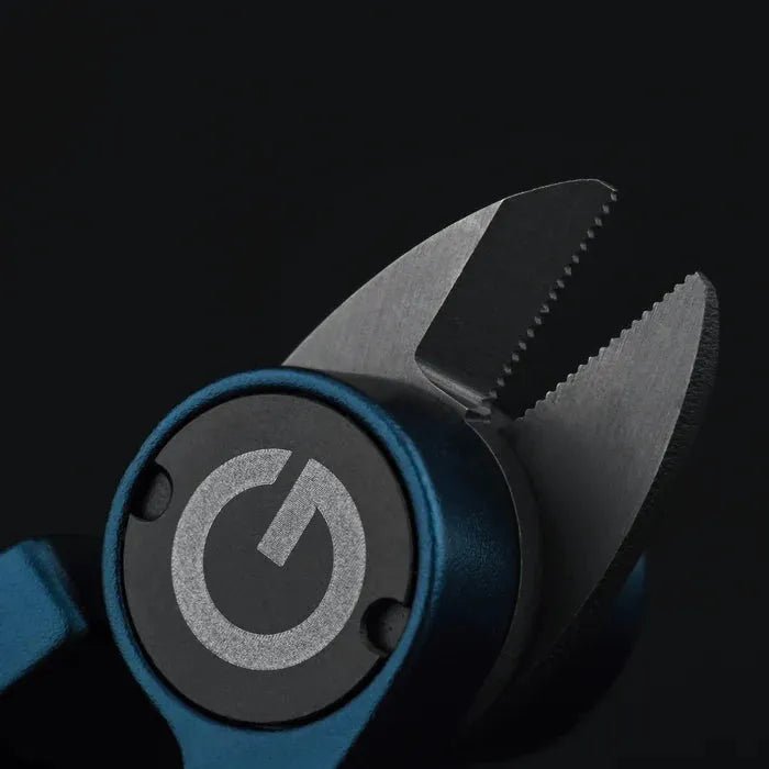Eine Nahaufnahme des Gomexus SharkBite Schnurknipser Combo von Gomexus mit gezackten Edelstahlklingen, einem dunkelblauen Griff und einem runden Emblem mit einem Machtsymbol auf der Seite vor einem schwarzen Hintergrund.