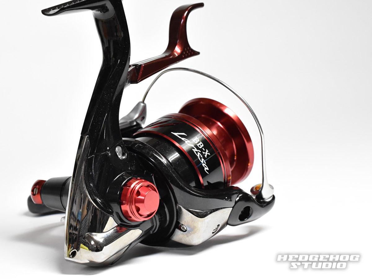 Eine Nahaufnahme des Hedgehog Studio Handle Screw Cap in Schwarz und Rot mit metallischen Akzenten, aufgenommen auf weißem Hintergrund. Das Hedgehog Studio-Logo erscheint in der unteren rechten Ecke.