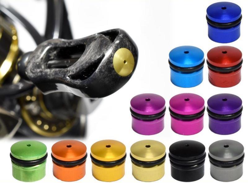 Links ist eine Nahaufnahme einer Hedgehog Studio Knob Cap | Daiwa Zaion von Hedgehog Studio auf einem Reifenventil zu sehen. Rechts sind zwölf weitere Kappen in verschiedenen Farben, inspiriert von Daiwa Zaion Knobs, ordentlich in drei Reihen angeordnet.