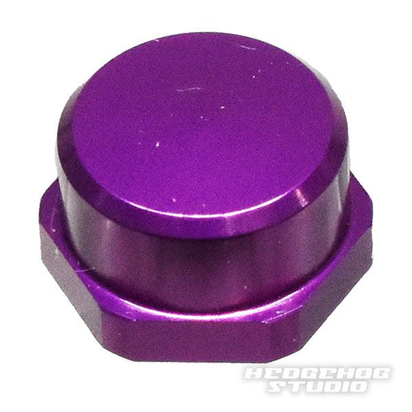 Eine metallic-lila Hedgehog Studio Shimano Kurbel-Kontermutter M7, sechseckig mit flacher Oberseite, ist auf weißem Hintergrund abgebildet. Das HEDGEHOG STUDIO Logo erscheint unten rechts. Perfektes Upgrade für originale Shimano Kurbeln.