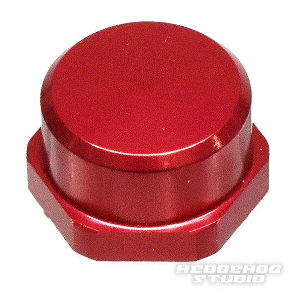 Auf weißem Untergrund ist eine rote, sechseckige Hedgehog Studio Shimano Griff-Kontermutter M7 für originale Shimano Kurbeln mit glatter, flacher Oberseite abgebildet. In der unteren rechten Ecke steht „HEDGEHOG STUDIO“.