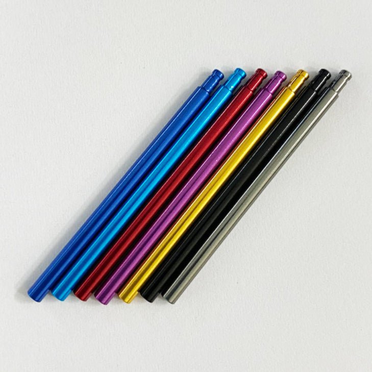 Sieben Metallstifte in verschiedenen Farben sind auf einer weißen Oberfläche aufgereiht - ideal, um Notizen oder Ideen zu notieren, während Sie Ihren Shimano 22 Aldebaran BFS mit dem Level Wind Shaft von Hedgehog Studio stimmen.