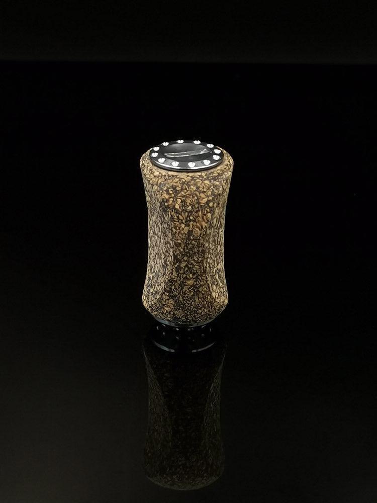 Ein RL-TNG Kork Knob 20mm | Slim | Universal Fit von RL-Angelrollentuning steht aufrecht auf einer glänzend schwarzen Oberfläche und wirft eine subtile Reflexion auf den dunklen Hintergrund, die an ein Angelrollen-Zubehör erinnert.