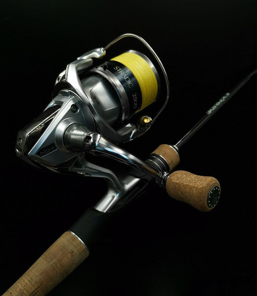 Eine Nahaufnahme eines RL-Angelrollentuning RL-TNG Kork Knob 20mm Grip (Universal Fit) auf einer Spinnrolle mit Edelstahlkugellagern und gelber Angelschnur vor schwarzem Hintergrund.