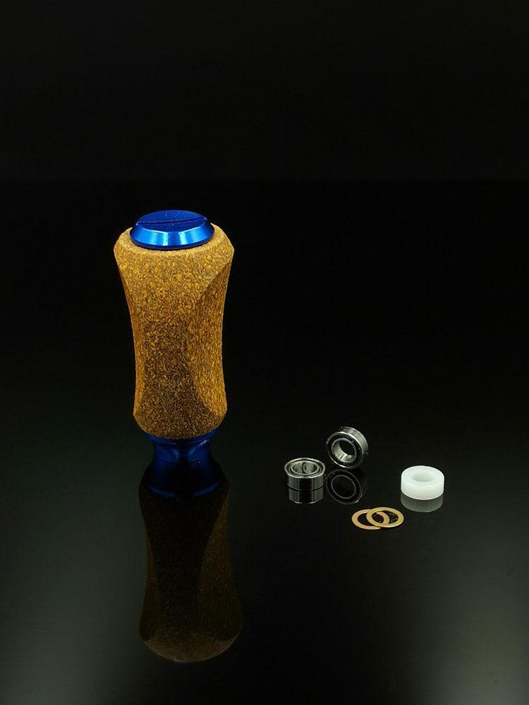 Ein RL-TNG Kork-Knopf von RL-Angelrollentuning mit blauem Ober- und Unterteil steht aufrecht neben Lagern, Unterlegscheiben und einem weißen Kunststoffteil auf schwarzem Hintergrund. Der Knopf hat eine universelle Passform und ist in mehreren Farben erhältlich.