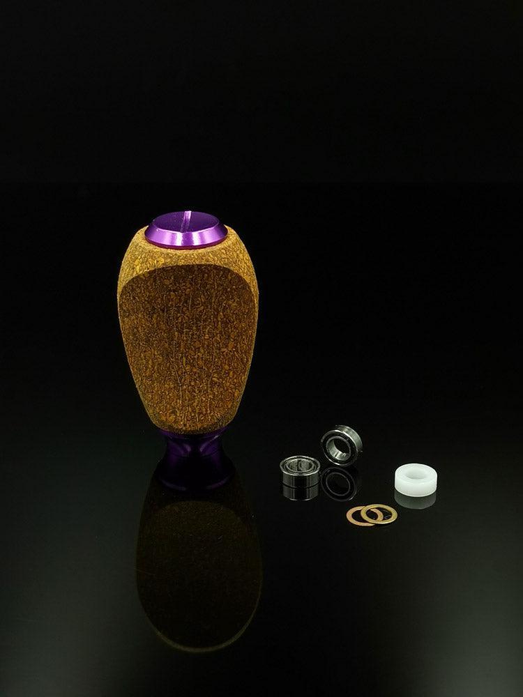 Der RL-Angelrollentuning RL-TNG Kork Knob (mehrfarbig, universell passend) steht aufrecht auf einer schwarzen Fläche, daneben befinden sich zwei Metalllager, ein Kunststoffring und zwei Unterlegscheiben – ideale Komponenten zum Aufrüsten Ihrer Angelrolle.