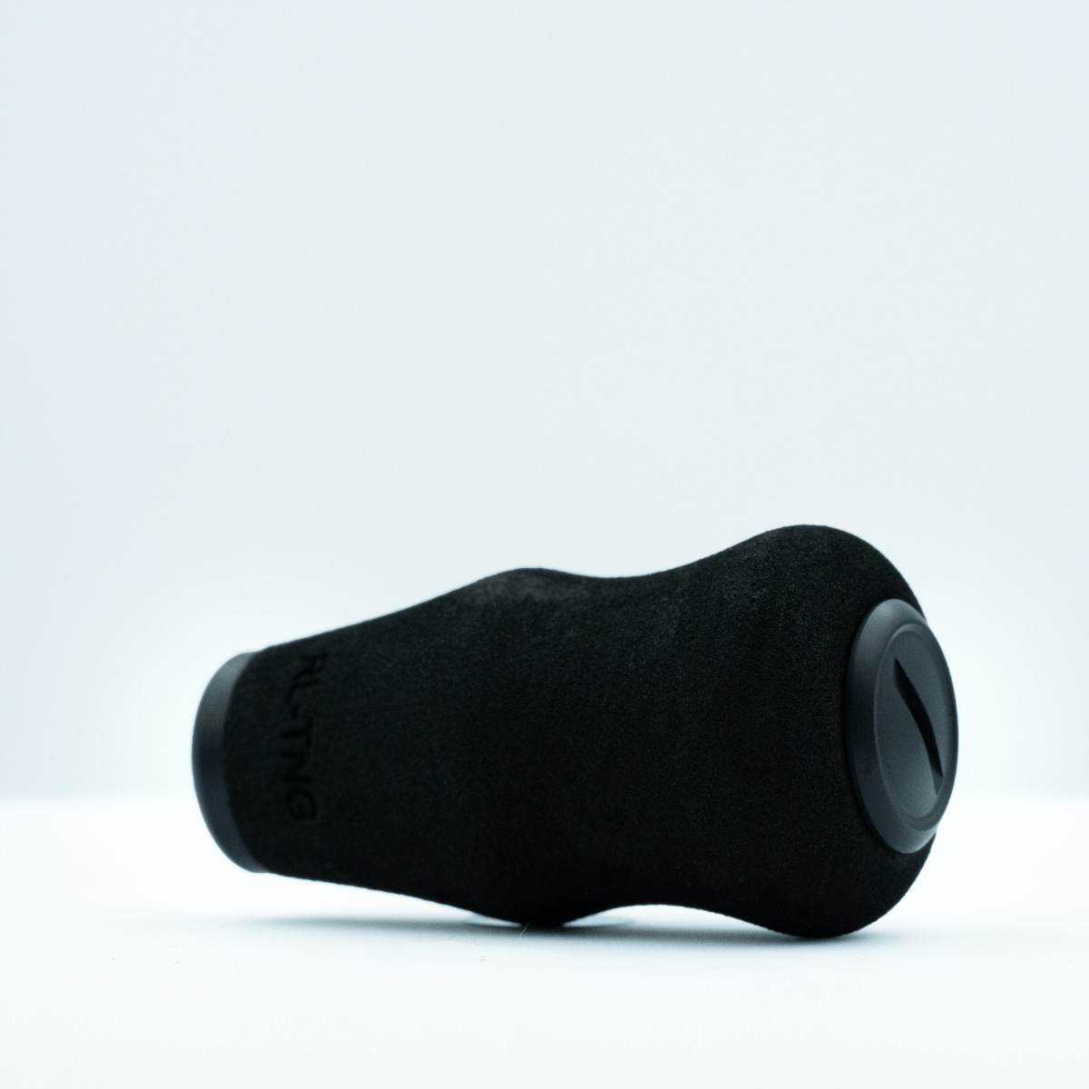 Der RL-TNG OCT 24 EVA-Knopf von RL-TNG in Schwarz mit matten und glänzenden Texturen liegt auf einer weißen Oberfläche. Seine geschwungene Form und das runde Enddetail bestehen aus EVA-Material für maximalen Grip.