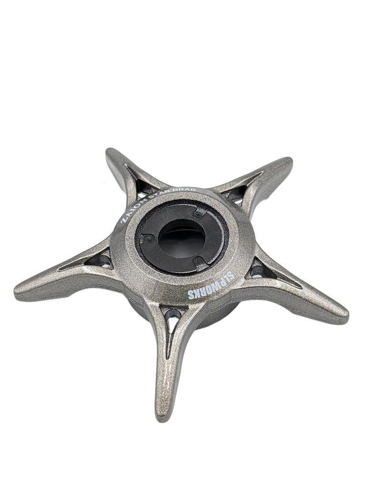 Ein silbernes, fünfzackiges Metallteil mit einem Loch in der Mitte und dem Aufdruck "SONDORS", fotografiert auf Weiß - ähnlich dem SLP Works Zaion Star Drag von SLP Works in Silber.