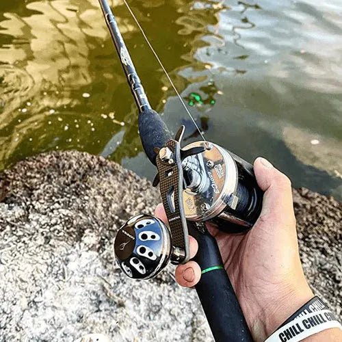 Eine Person greift einen Gomexus Carbon Handle 75 mm mit 38 mm Power Knob (8x5mm), steht über Felsen in trübem Wasser und trägt ein "CHILL CHILL"-Armband.