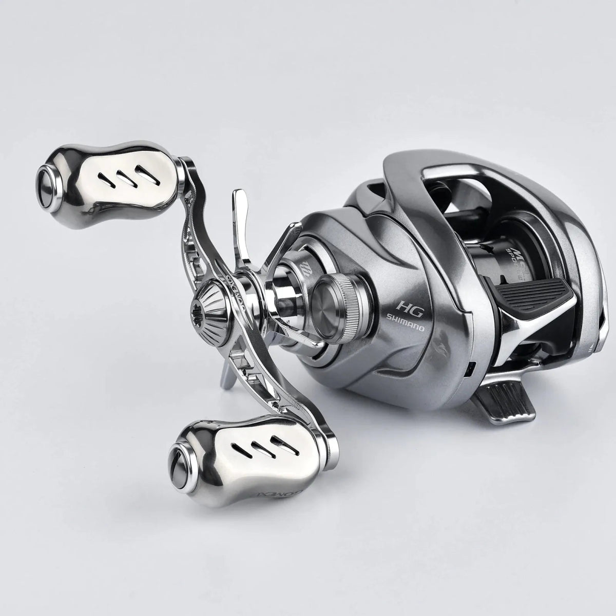 Eine Nahaufnahme einer Gomexus Sternbremse 60 mm Angelrolle für Shimano, mit zwei Griffen und Aluminium Sternbremse, auf einer schlichten hellgrauen Oberfläche.