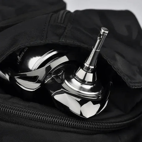 Eine Nahaufnahme von glänzenden Metallobjekten, möglicherweise Golfschlägerköpfe, die teilweise in einer schwarzen Tasche mit offenem Reißverschluss zu sehen sind. Die reflektierende Oberfläche weist einige Licht- und Schattenakzente auf.