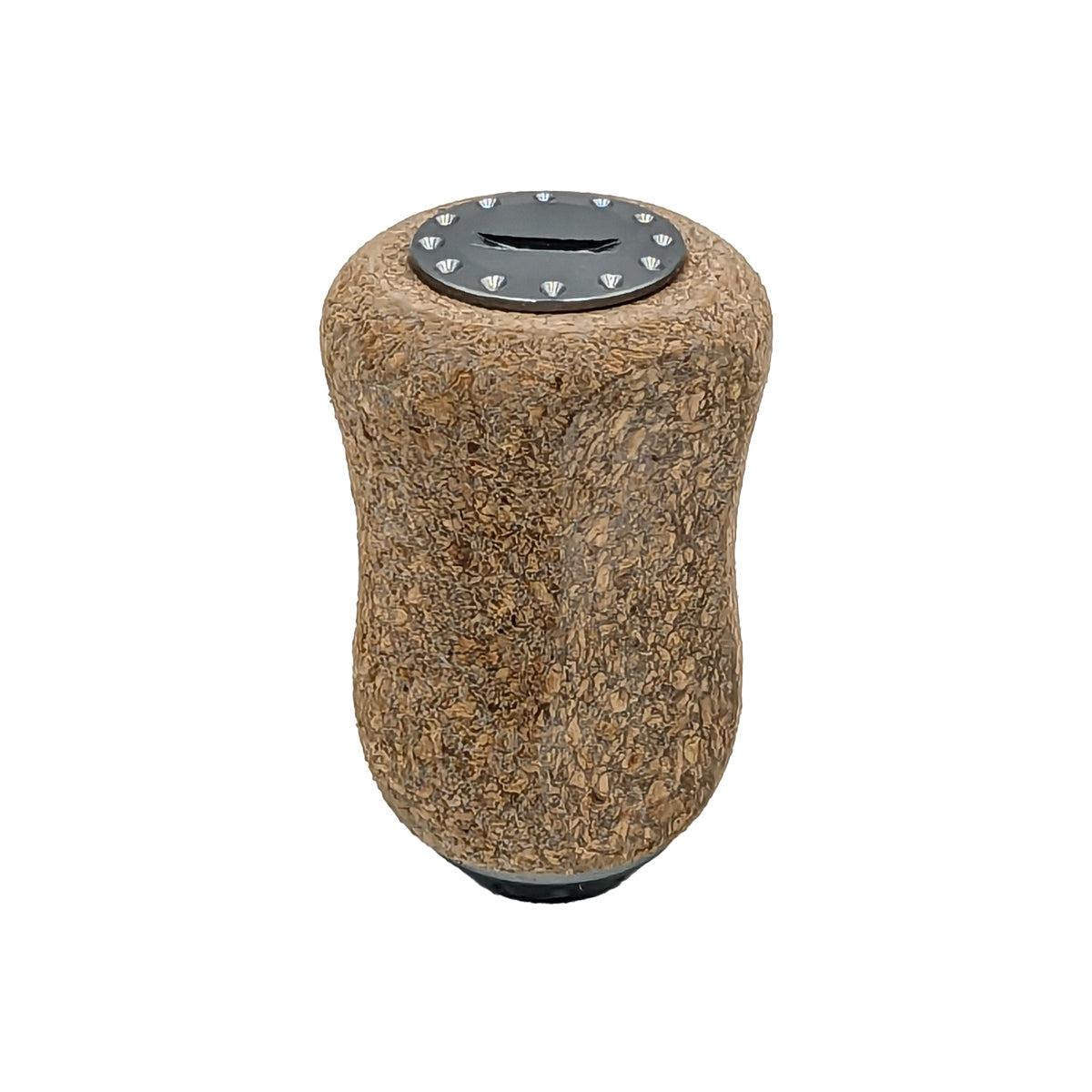 Der RL-Angelrollentuning RL-TNG Korkknopf 20mm ist ein brauner, strukturierter zylindrischer Griff mit einer schwarzen Kunststoff-Schlitzspitze, die mit kleinen Dreiecken auf weißem Hintergrund markiert ist. Universell passend für verschiedene Anwendungen.
