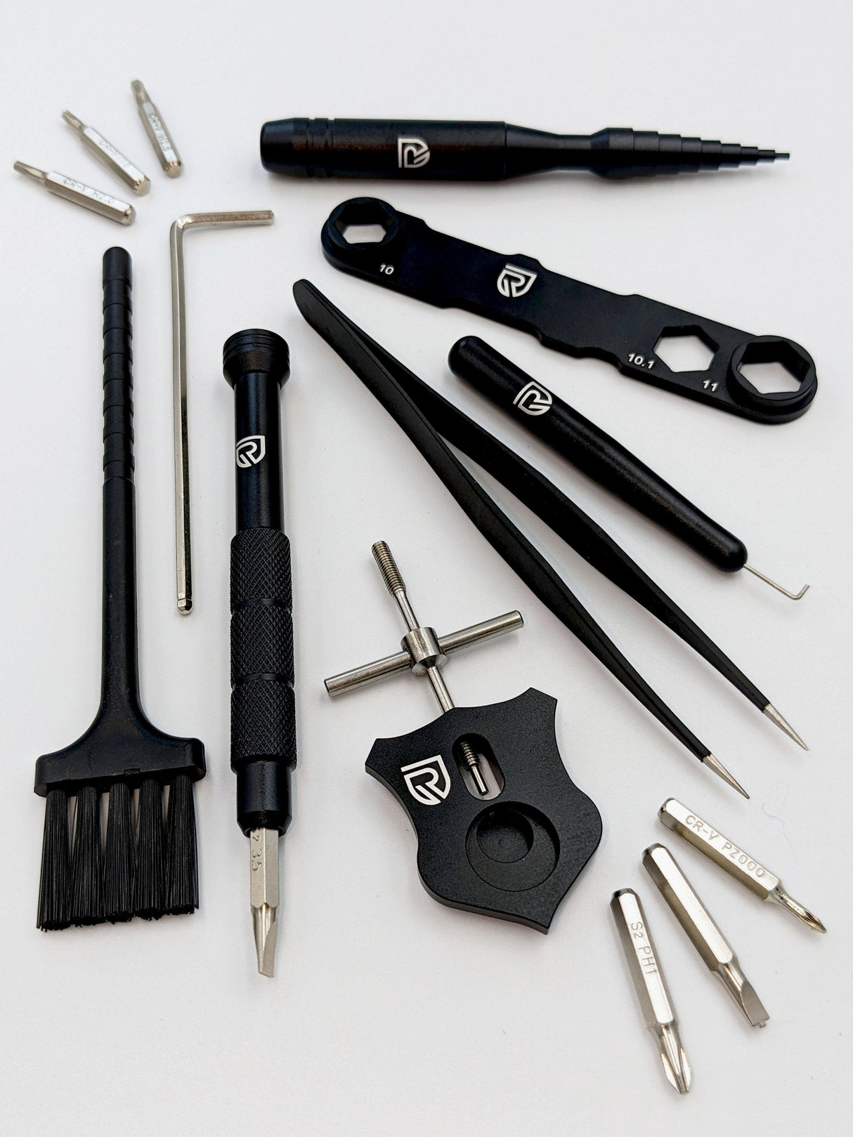 Das RL-TNG Wartungskit von RL-Angelrollentuning umfasst schwarze und silberne Präzisionsschraubendreher, Schraubenschlüssel, Pinzette, Bürste, Sechskantbits und Multitool – idealer Werkzeugkoffer für Baitcaster Angelrollen, alle mit passendem Logo.