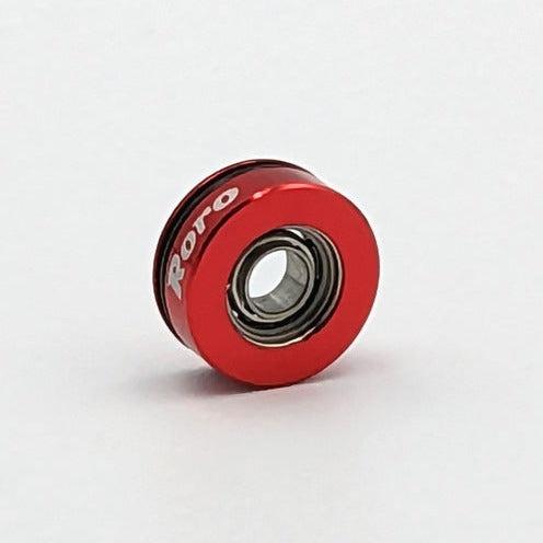 Ein kleines rotes Roro BFS Keramik Kugellager von Roro Lure, auf dessen Seite in weißer Farbe "Roto" aufgedruckt ist, wird vor einem schlichten weißen Hintergrund fotografiert.