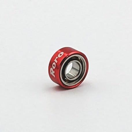 Ein kleines, rotes Roro Köder Roro BFS Keramik Kugellager mit "Roro" in weißer Schrift auf dem Gehäuse, fotografiert vor einem schlichten weißen Hintergrund.