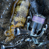 Ein Tintenfisch liegt in einem schwarzen Netz neben einer metallischen Shimano-Rolle, die mit der Gomexus-Doppelkurbel 98–82 mm mit T20-Knöpfen ausgestattet ist und ihr elegantes Design zur Schau stellt.