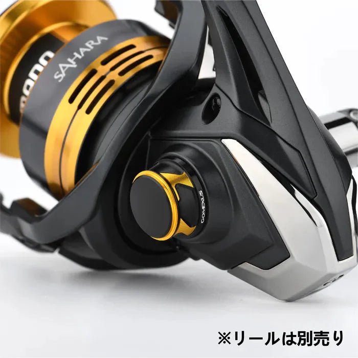 Nahaufnahme einer schwarz-goldenen Angelrolle mit montierter Gomexus-Griffschraubkappe (kompatibel mit Daiwa & Shimano, Größen 2000–5000). Der Markenname Gomexus ist sichtbar; in der unteren rechten Ecke erscheint japanischer Text.