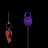 Ein rot-schwarzer Knotentool Angelschnurclip und ein violetter Gomexus SharkBite Schnurknipser Combo werden vor einem schwarzen Hintergrund gezeigt, beide mit dem Gomexus Branding versehen.