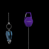 Eine Gomexus SharkBite Schnurknipser Combo, bestehend aus einem blauen Angelschnurknipser und einem lila einziehbaren Zinger von Gomexus, hängt vor einem schwarzen Hintergrund, verbunden durch dünne Drähte.