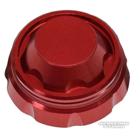 Auf einem weißen Hintergrund ist ein roter, metallischer Hedgehog Studio Handle Screw Cap mit geriffelten Kanten und einer glatten, flachen Oberseite mit einem schwachen HEDGEHOG STUDIO-Wasserzeichen in der unteren rechten Ecke abgebildet.