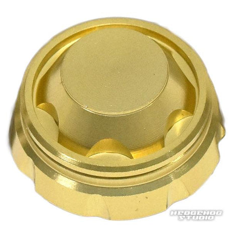 Eine Nahaufnahme des Hedgehog Studio Handle Screw Cap – ein metallischer, goldfarbener Schraubverschluss mit flacher Oberseite und geriffelten Seiten – vor einem weißen Hintergrund mit „HEDGEHOG STUDIO“ in der unteren rechten Ecke.