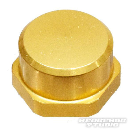 Auf weißem Hintergrund ist eine goldfarbene, sechseckige Hedgehog Studio Shimano Handle Locknut M7 für Original Shimano Kurbeln abgebildet, in der unteren rechten Ecke ist schwach HEDGEHOG STUDIO zu erkennen.