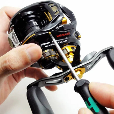 Jemand repariert mit einem Schraubenzieher eine schwarz-goldene Angelrolle mit dem RL-Angelrollentuning Einbau Hybrid Keramik Kugellager Set (ABEC 9) und hält die Rolle dabei mit einer Hand fest, während er die Einstellungen vornimmt.