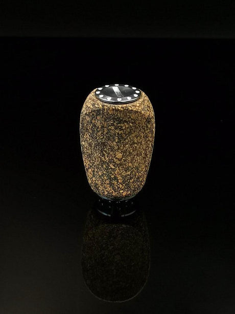 Der RL-TNG Korkknopf 20 mm | Schlank | Universal Fit von RL-Angelrollentuning ist ein kleiner, zylindrischer Knopf mit strukturiertem Korkkörper, schwarzer Oberseite und metallischen Edelstahlkugellager-Akzenten, der auf einer glänzend schwarzen Oberfläche vor dunklem Hintergrund steht.