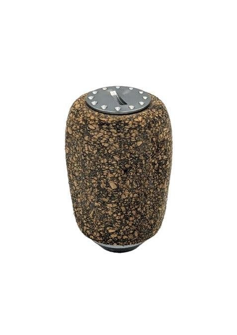 Der RL-TNG Kork Knob 20 mm von RL-Angelrollentuning ist ein schlanker, universell passender zylindrischer Knauf mit einer braun und schwarz gesprenkelten Korkstruktur und einer metallischen Oberseite mit kleinen dreieckigen Formen.