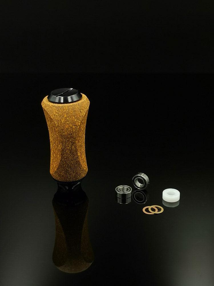 Der RL-TNG Kork Knob von RL-Angelrollentuning, ein universell passender, mehrfarbiger Griff, ist auf einer reflektierenden schwarzen Oberfläche mit zwei Metalllagern, einem weißen Kunststoffring und zwei rechts angeordneten metallischen Unterlegscheiben abgebildet.