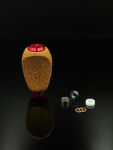 Der RL-TNG Kork Knob von RL-Angelrollentuning besticht durch seine Holzstruktur und die rote Oberseite. Er ist aufrecht auf einer schwarzen, reflektierenden Oberfläche abgebildet und mit zwei Lagern, einem weißen Abstandshalter und zwei goldenen Unterlegscheiben ausgestattet – ideal für Ihr Angelrollen-Setup.