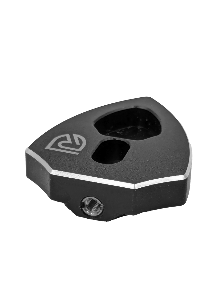 Der RL-Angelrollentuning RL-TNG Spool Bearing Pin Remover mit Kreuzschlüssel ist ein schwarzes, geometrisches Tuning-Tool für Angelrollen mit zwei Löchern, abgeschrägter Kante, eingraviertem Logo und sichtbarer Sechskantschraube, dargestellt auf einem schlichten schwarzen Hintergrund.