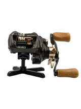 Auf dem RL-Angelrollentuning Röllenständer DK | Reel Stand sitzt eine schwarz-goldene Baitcasterrolle mit Holzgriffen und wird elegant vor einem weißen Hintergrund präsentiert.