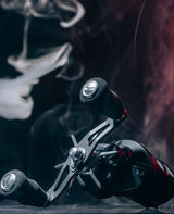 Eine Nahaufnahme der Angelrolle RL-TNG OCT 24 EVA Knob von RL-TNG mit einem Griff aus Kohlefaser und schwarzen EVA-Griffen vor einem dunklen Hintergrund mit wirbelndem weißem Rauch oder Dampf.