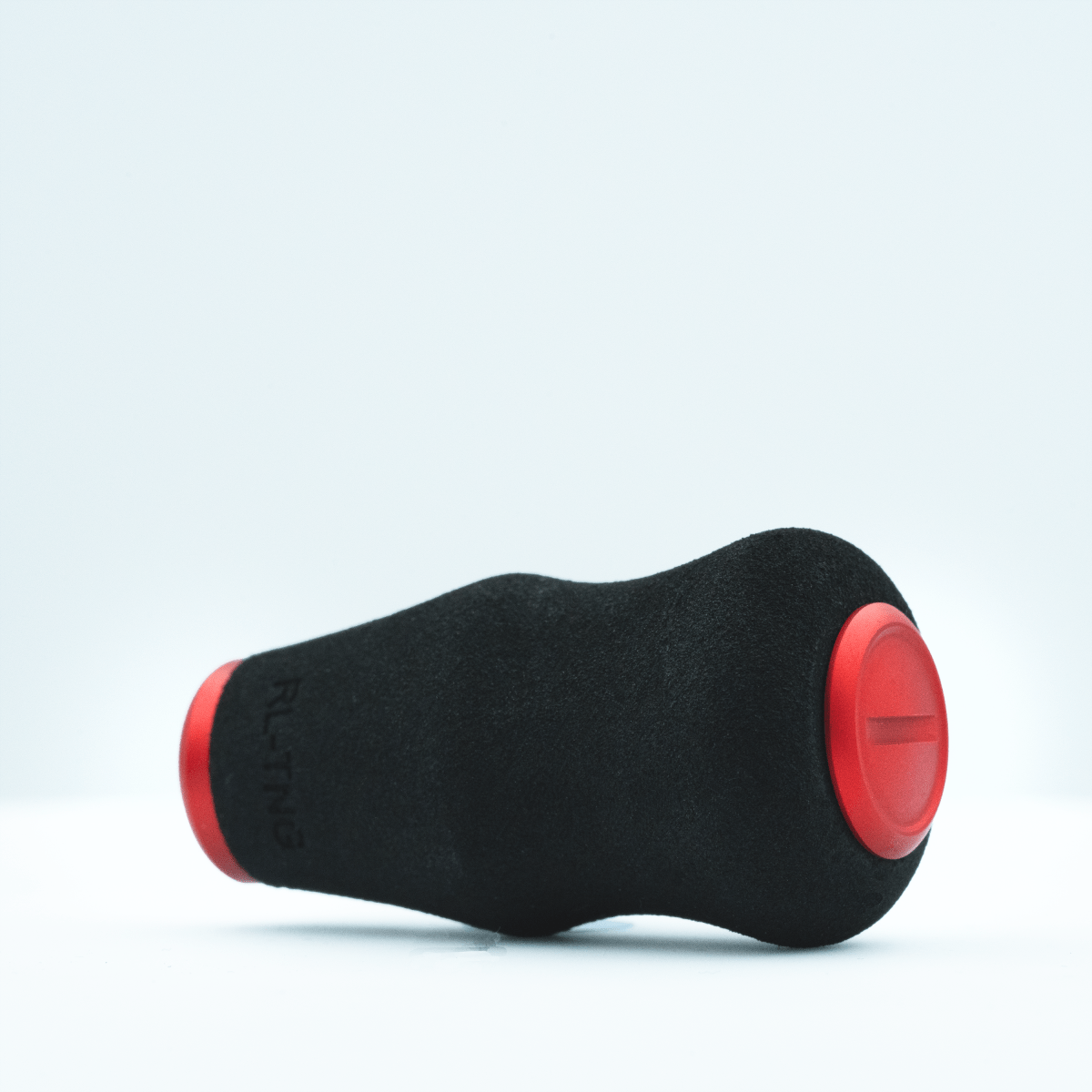 Der RL-TNG OCT 24 EVA Knob von RL-TNG ist ein schwarzer, ergonomischer Angelrollenknauf aus EVA mit roten, abgerundeten Enden und waagerechter Rille – für maximalen Grip. Das Produkt liegt waagerecht auf weißem Hintergrund.