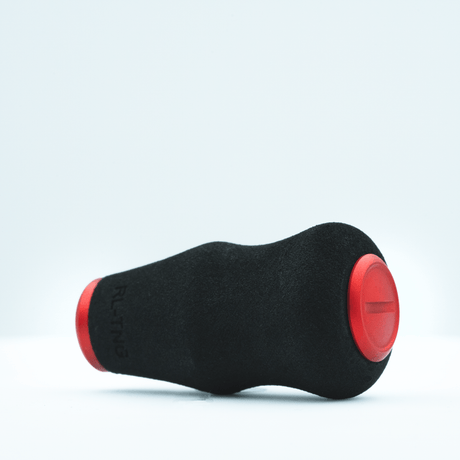 Der RL-TNG OCT 24 EVA Knob von RL-TNG ist ein schwarzer, ergonomischer Angelrollenknauf aus EVA mit roten, abgerundeten Enden und waagerechter Rille – für maximalen Grip. Das Produkt liegt waagerecht auf weißem Hintergrund.
