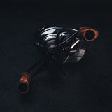 Nahaufnahme vom SLP Works i Shape Wood Knob Limited Edition – perfekt fürs Reel-Tuning! Der stilvolle Holzknauf glänzt mit einzigartiger Maserung und coolen Metall-Details vor dunklem Hintergrund. Mit dem richtigen Licht werden die schicken Akzente richtig in Szene gesetzt. Wenn du deinem Angelsetup ein Upgrade verpassen willst, geht’s nicht edler!.