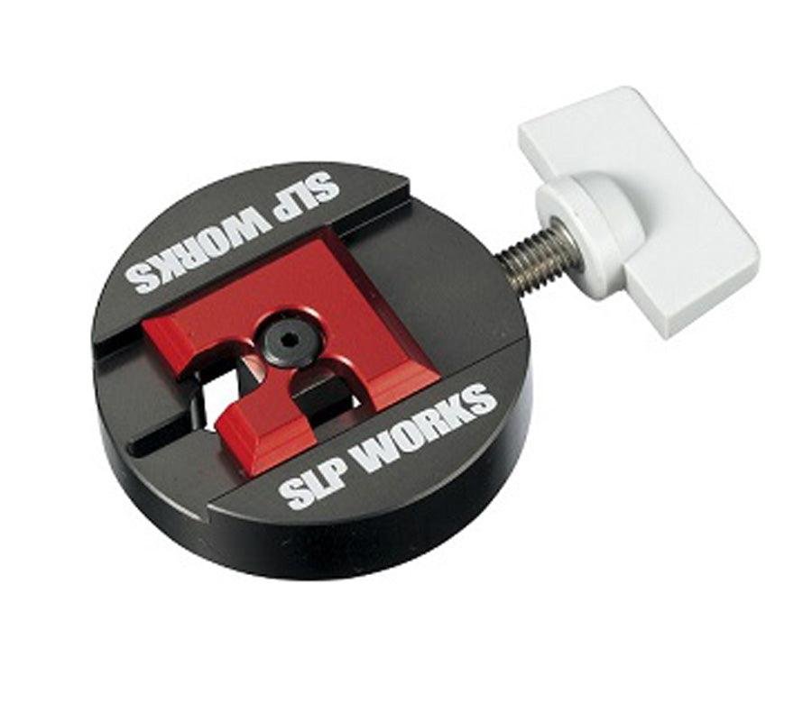 Der SLP Works Spool BB Remover II ist ein rundes, schwarz-rotes Metallwerkzeug mit einem weißen T-förmigen Einstellknopf und gefräster roter Mitte - ideal für Baitcasting-Rollen, von SLP Works.