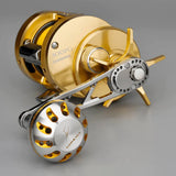 Eine goldene Shimano Conquest 300PG-Rolle gepaart mit einem 85-mm-Gomexus-Aluminiumgriff und einem 38-mm-Power-Knopf (7 x 4 mm) in Silber und Gold, aus einem Winkel gezeigt, der die Spule, die Bremseinstellung und die Markendetails zeigt.