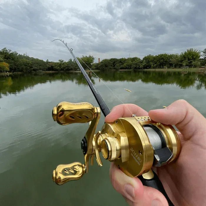 Eine Person hält einen 90 mm langen Gomexus Gold Aluminium-Griff mit 22 mm Titanknöpfen (7 x 4 mm), der an einer Angelrute befestigt ist, und wirft über einen ruhigen See, der von Bäumen unter einem bewölkten Himmel umgeben ist.